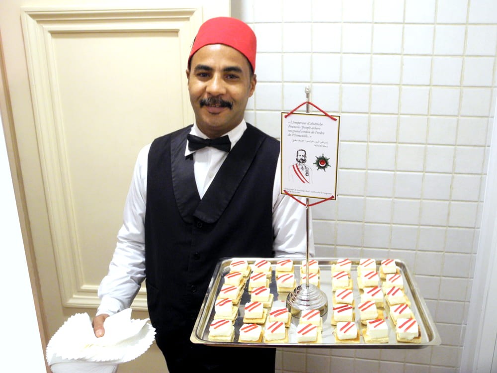 Serveur et plateau. Bouchée inspirée de l'Empereur d'Autrice François Joseph. Fromage et poivron mariné.